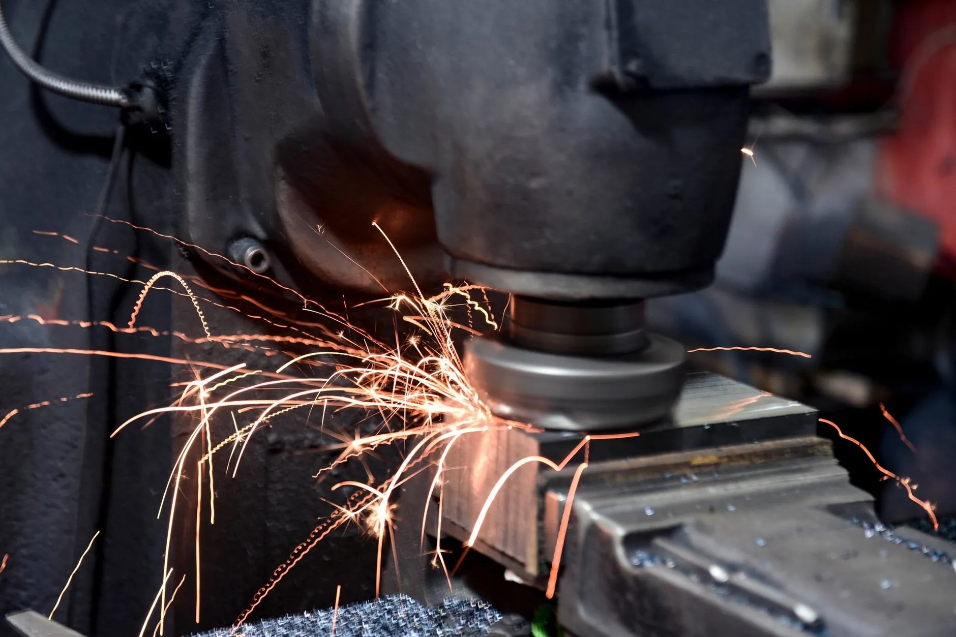 A grinding wheel dressing a steel edge before blasting, sparks arcing away