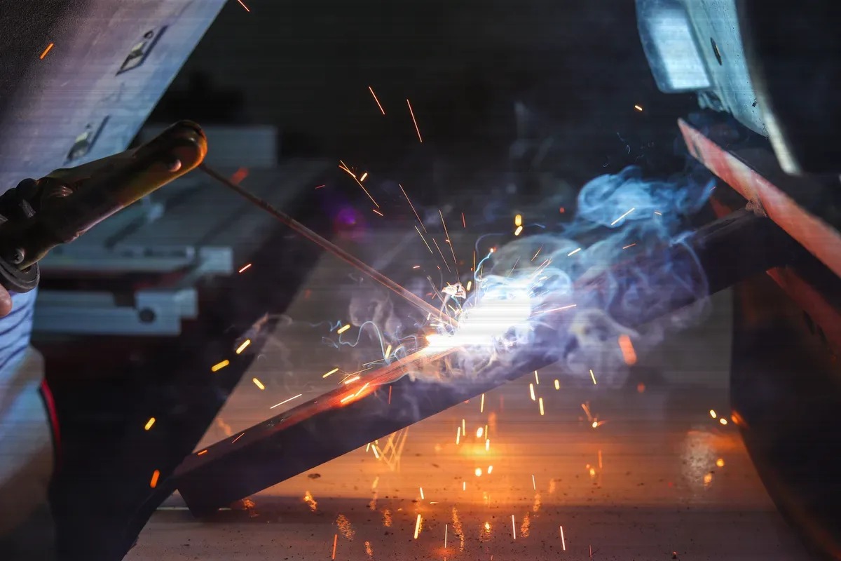 A MIG arc striking on a steel joint, sparks lifting off the weld pool